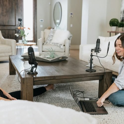 person in white shirt using black laptop computer on brown wooden table